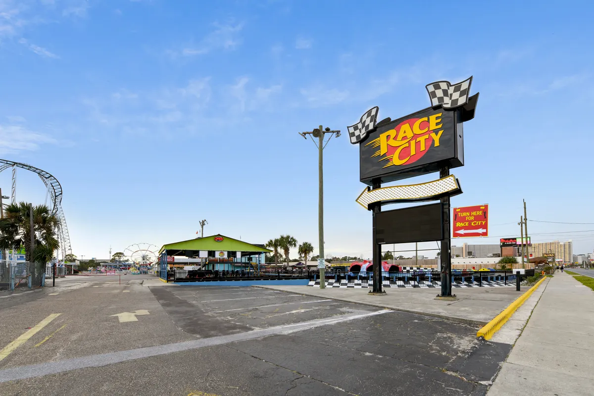 The dynamic exterior of Race City, featuring a bold sign, a go-kart track, and amusement rides in the background. Families and kids are depicted enjoying thrilling activities.
