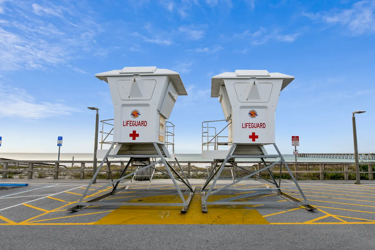 This image captures a classic beach scene featuring lifeguard towers, soft sand, and the expansive ocean stretching to the horizon. The relaxed atmosphere is ideal for sunbathing, beach strolls, and watching sunsets, providing a quintessential coastal vibe.