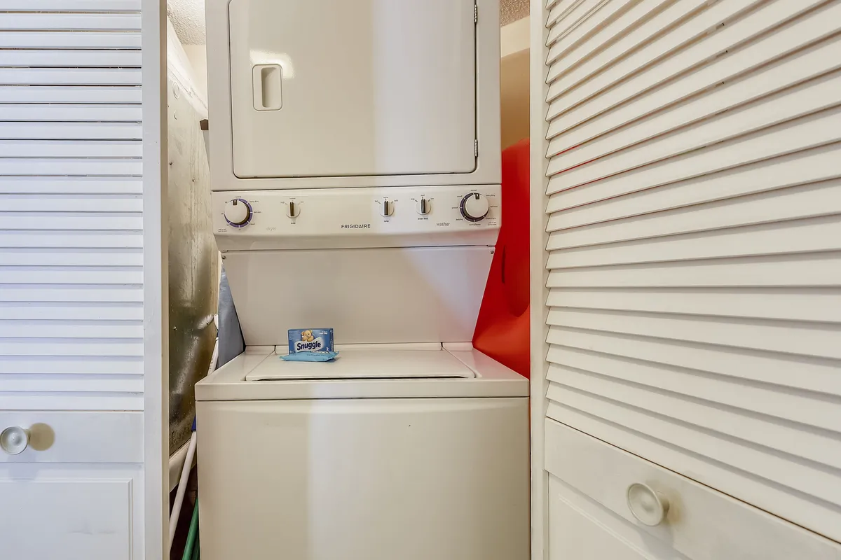 A stacked washer and dryer unit neatly tucked into a nook, with a box of fabric softener sheets visible, emphasizing the in-unit laundry amenity.